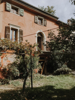 Italienisches Bauernhaus mit kleinem Balkon und wilden Pflanzen davor 